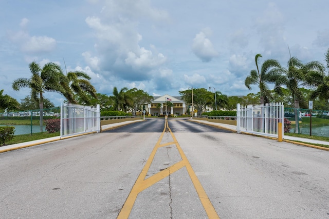 view of street with curbs, a gate, a gated entry, sidewalks, and street lighting