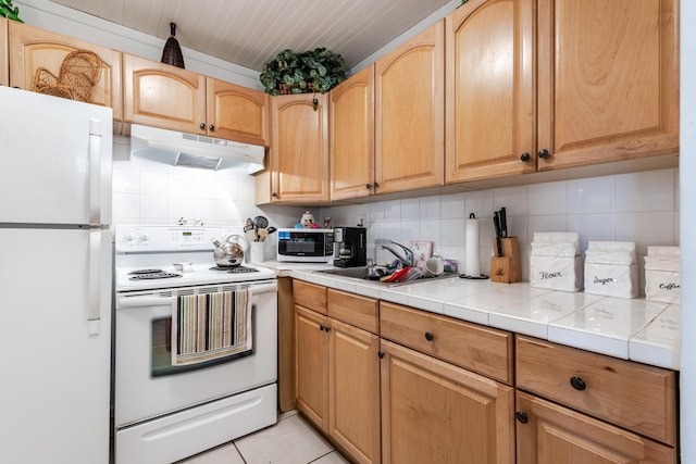 kitchen featuring under cabinet range hood, white appliances, tasteful backsplash, and a sink