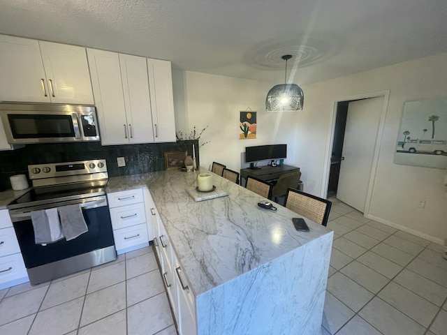 kitchen with light tile patterned floors, a peninsula, white cabinets, appliances with stainless steel finishes, and decorative backsplash