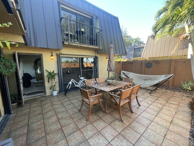 view of patio / terrace featuring outdoor dining area, fence, and a balcony