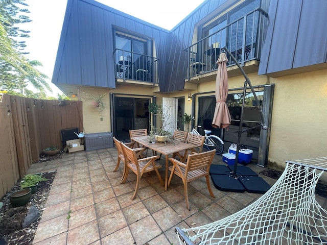 view of patio / terrace featuring outdoor dining space, a fenced backyard, and a balcony