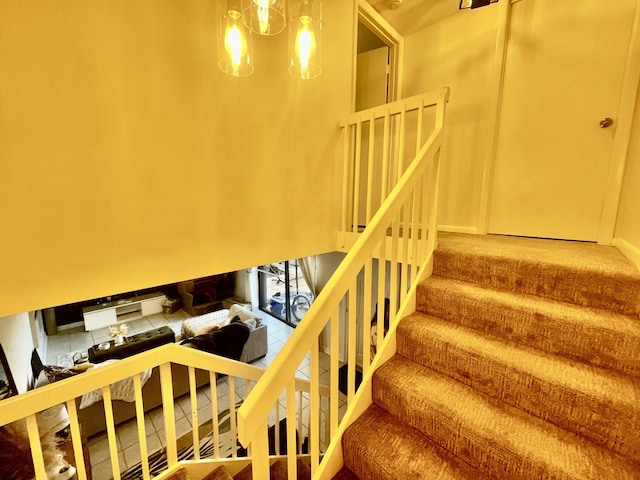 staircase featuring tile patterned flooring and a notable chandelier