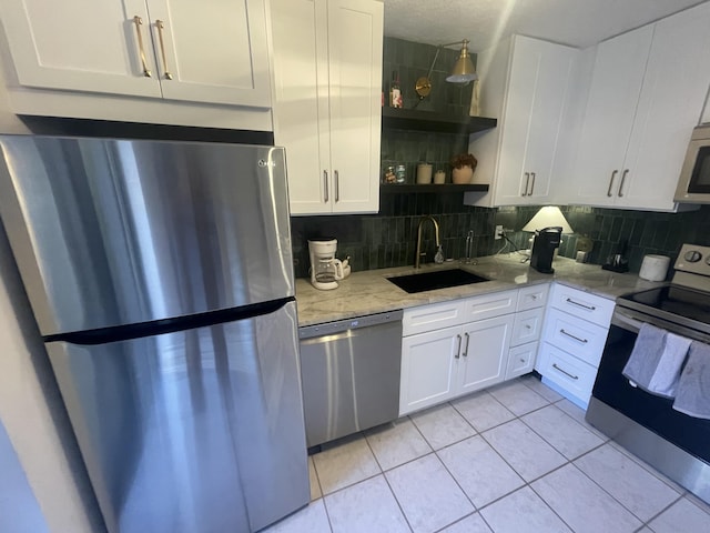 kitchen with light tile patterned floors, open shelves, decorative backsplash, appliances with stainless steel finishes, and a sink