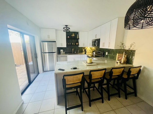 kitchen featuring a peninsula, tasteful backsplash, appliances with stainless steel finishes, and a sink