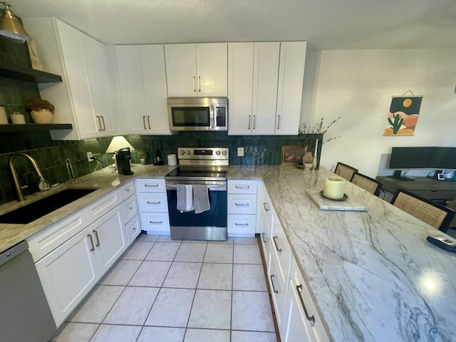 kitchen featuring light tile patterned floors, stainless steel appliances, open shelves, a sink, and light stone countertops