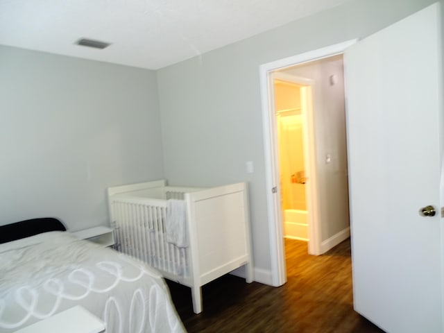 bedroom featuring dark hardwood / wood-style floors and a nursery area