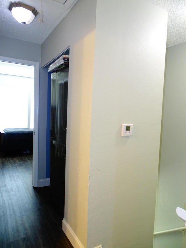 hallway with a textured ceiling and dark hardwood / wood-style floors