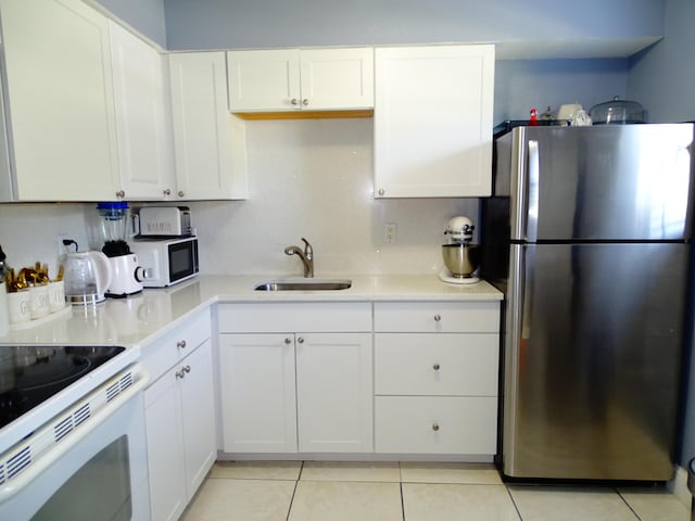 kitchen with white cabinetry, white appliances, sink, and light tile patterned floors