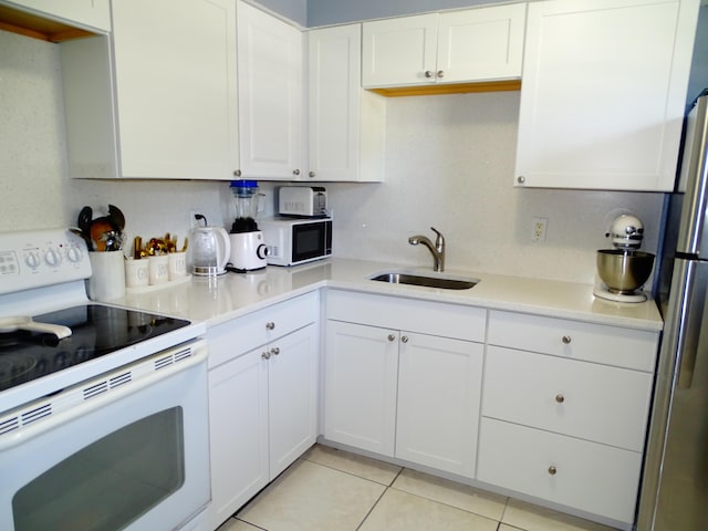 kitchen featuring white appliances, sink, decorative backsplash, light tile patterned floors, and white cabinetry