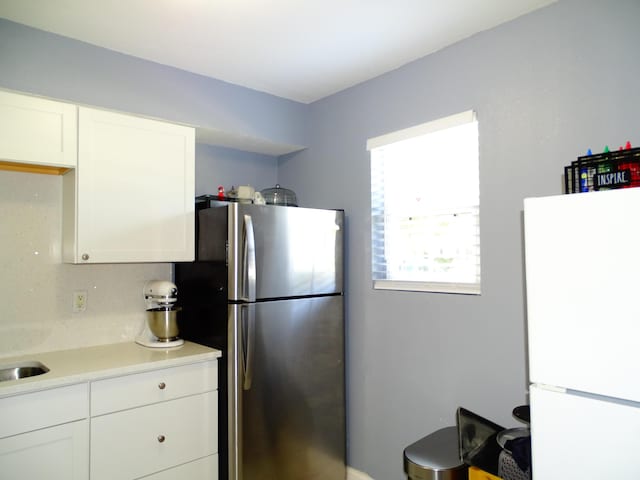 kitchen featuring backsplash, stainless steel refrigerator, white cabinetry, and white fridge