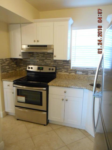 kitchen with white cabinetry, light stone countertops, light tile patterned floors, white fridge, and stainless steel range with electric cooktop