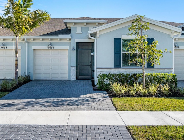 view of front of house with a garage, brick siding, decorative driveway, and stucco siding