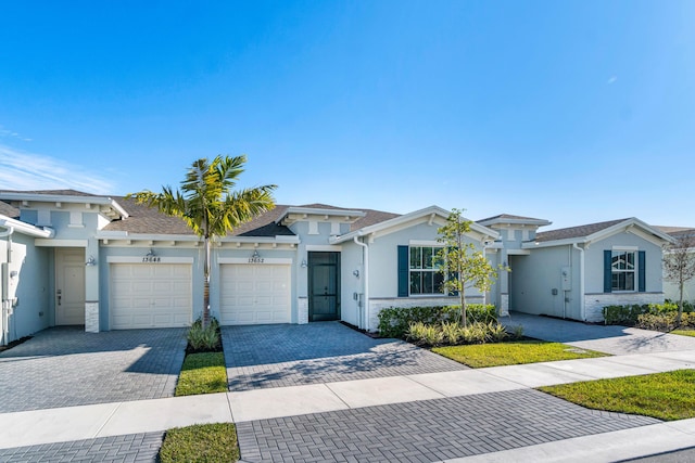 view of front of house featuring decorative driveway, an attached garage, and stucco siding