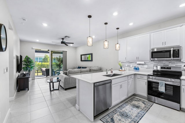 kitchen featuring a sink, white cabinetry, open floor plan, light countertops, and appliances with stainless steel finishes