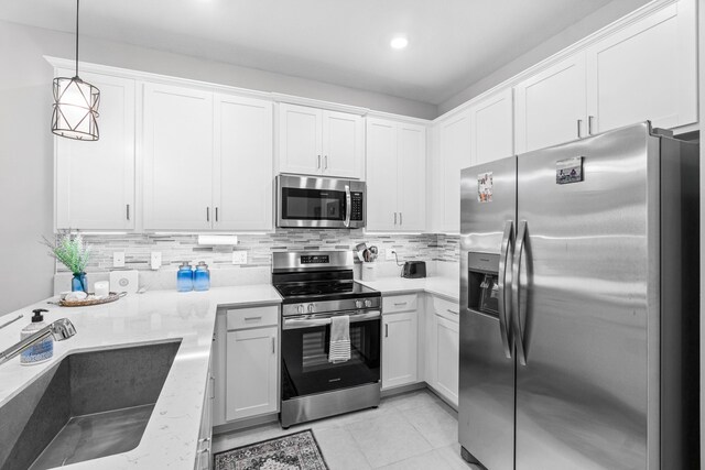 kitchen featuring white cabinetry, sink, hanging light fixtures, light tile patterned floors, and appliances with stainless steel finishes