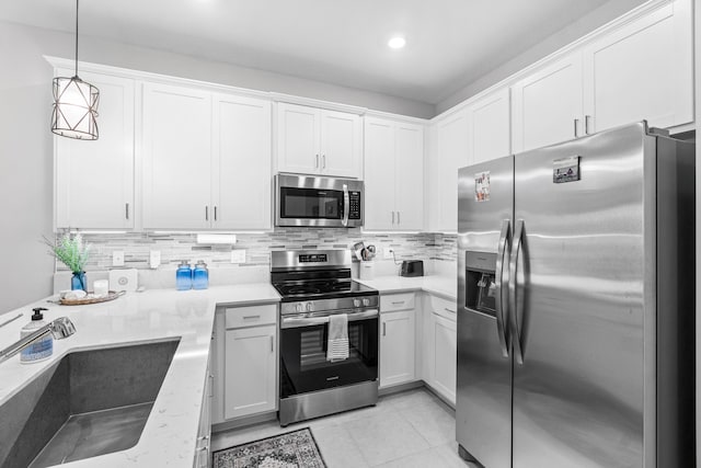 kitchen featuring a sink, white cabinetry, appliances with stainless steel finishes, tasteful backsplash, and decorative light fixtures