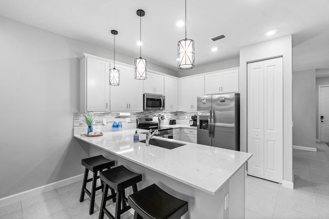 kitchen with sink, hanging light fixtures, kitchen peninsula, white cabinets, and appliances with stainless steel finishes