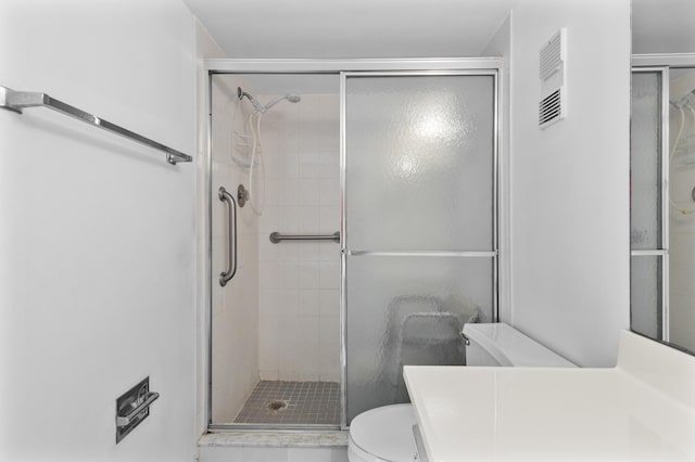 bathroom featuring vanity, toilet, and a shower with door