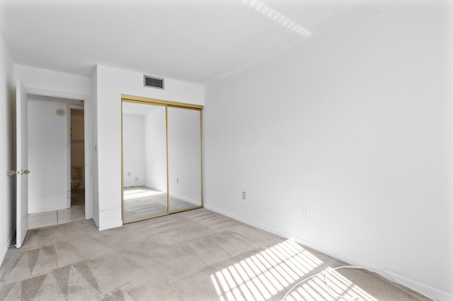 unfurnished bedroom with a closet and light carpet