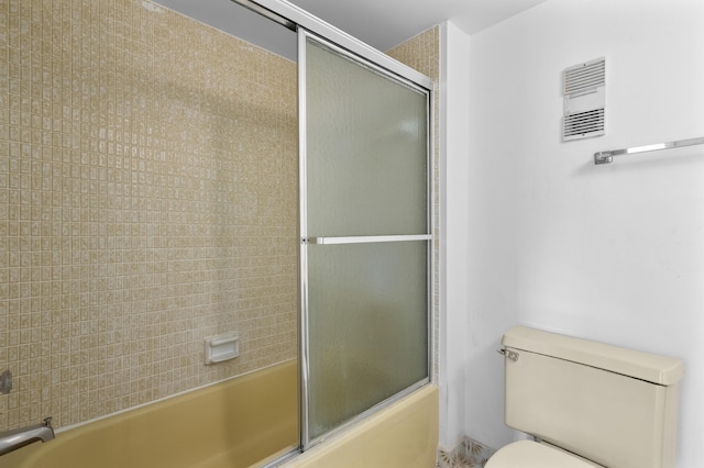 bathroom featuring combined bath / shower with glass door and toilet