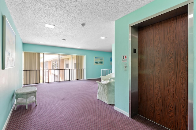 hall with a textured ceiling, elevator, and carpet flooring