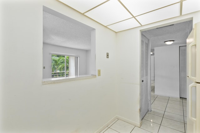 corridor with a textured ceiling and light tile patterned floors