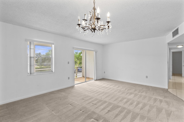 unfurnished room with light carpet, an inviting chandelier, and a textured ceiling