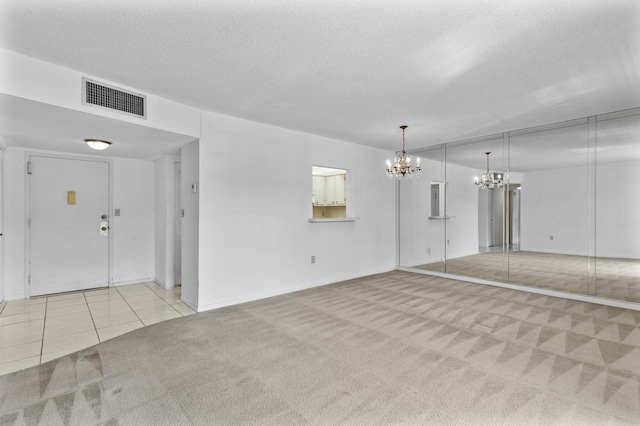 unfurnished living room with a textured ceiling, light carpet, and a notable chandelier