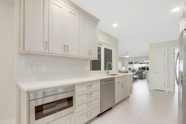 kitchen featuring appliances with stainless steel finishes, backsplash, ceiling fan, sink, and light tile patterned flooring