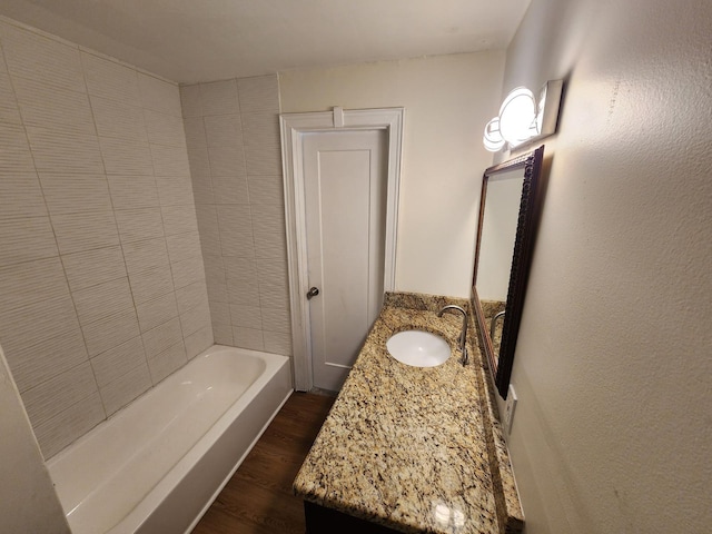 bathroom with vanity, wood-type flooring, and a tub to relax in