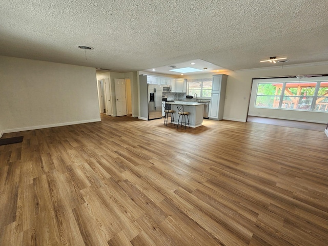 unfurnished living room with a textured ceiling and light wood-type flooring