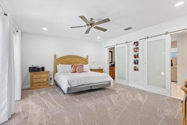 carpeted bedroom featuring connected bathroom, a barn door, and ceiling fan