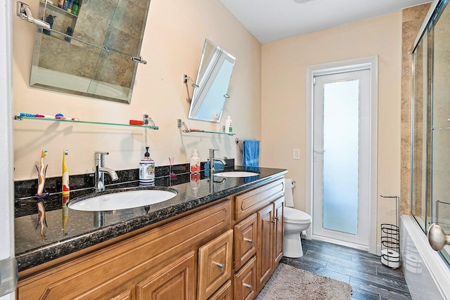 full bathroom with combined bath / shower with glass door, vanity, and toilet