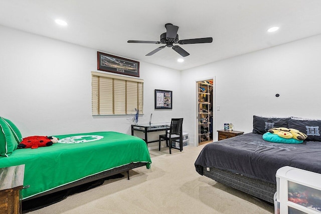 carpeted bedroom with a walk in closet, ceiling fan, and a closet