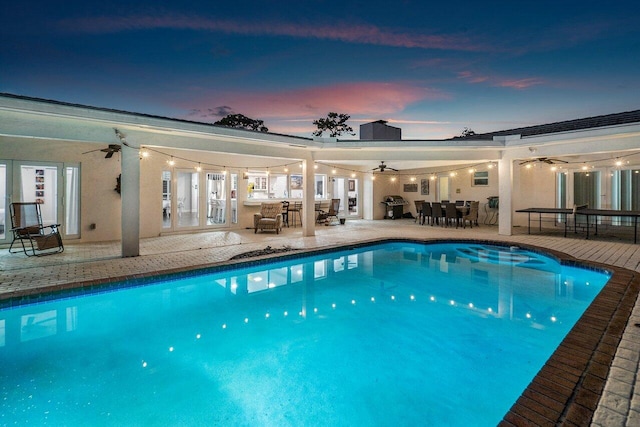 pool at dusk with a patio area