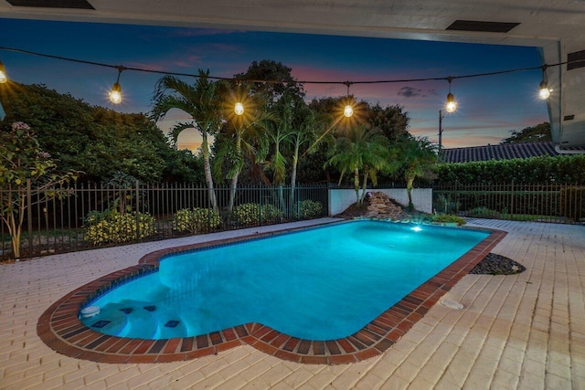 pool at dusk featuring a patio area