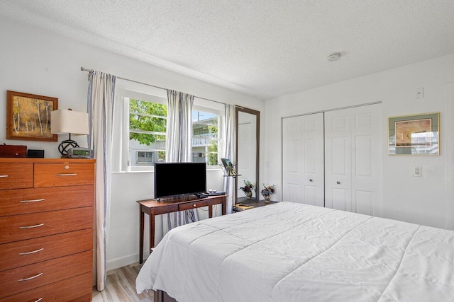 bedroom with a closet, a textured ceiling, and light hardwood / wood-style flooring