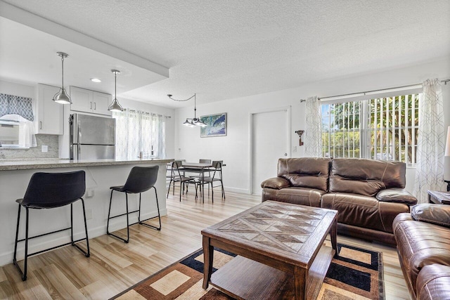 living room with a textured ceiling and light wood-type flooring