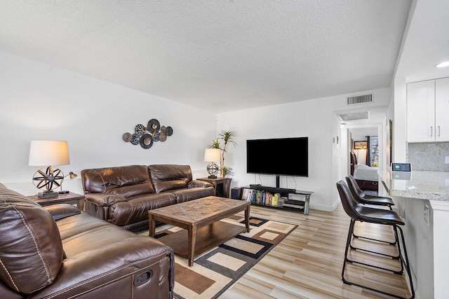 living room featuring light wood-type flooring and a textured ceiling