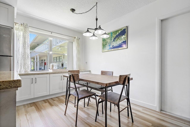 dining area featuring a notable chandelier, a textured ceiling, and light hardwood / wood-style flooring