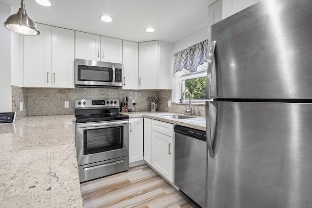 kitchen featuring white cabinets, hanging light fixtures, sink, and appliances with stainless steel finishes