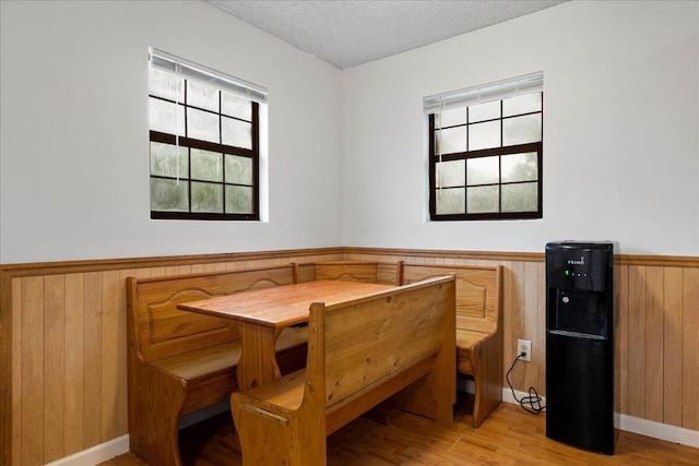 dining space featuring wood walls, light hardwood / wood-style floors, and a textured ceiling