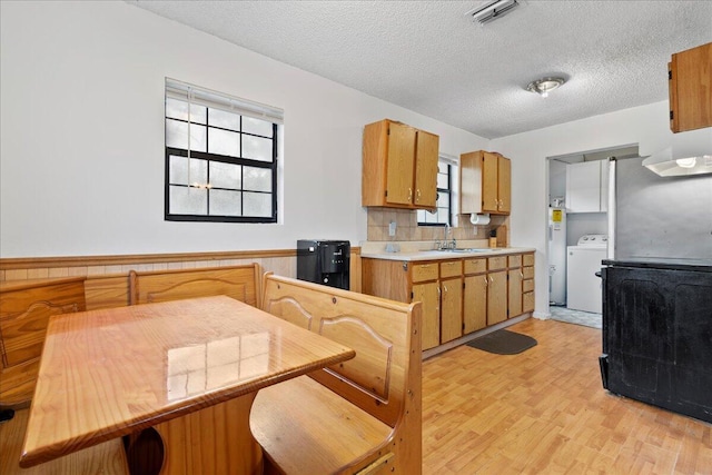 kitchen featuring washer / dryer, a textured ceiling, light hardwood / wood-style floors, and sink