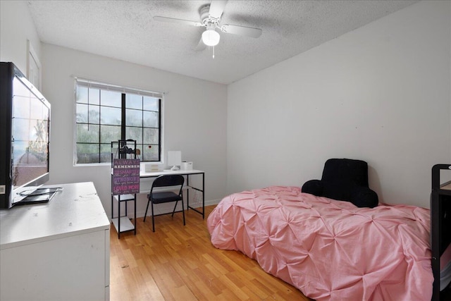 bedroom with ceiling fan, light hardwood / wood-style floors, and a textured ceiling