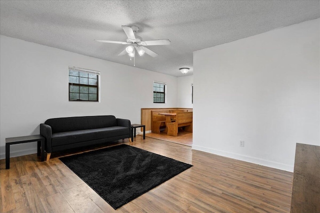 living room with wood-type flooring, a textured ceiling, and ceiling fan