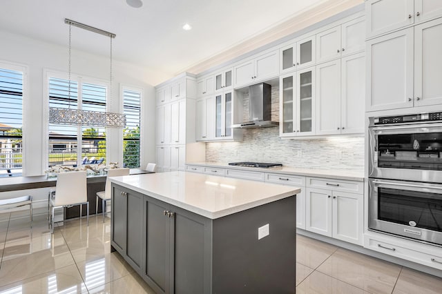 kitchen featuring white cabinets, wall chimney exhaust hood, pendant lighting, and stainless steel appliances