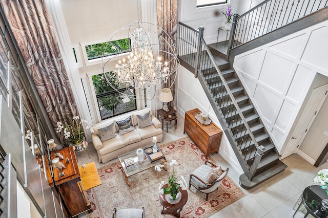 tiled living room featuring a towering ceiling and an inviting chandelier