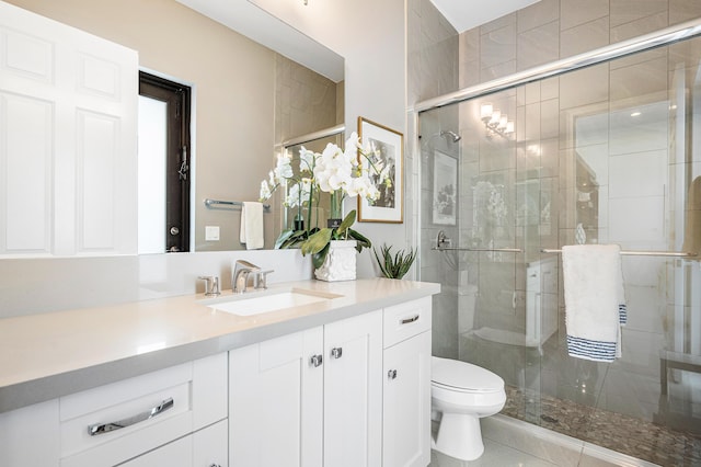 bathroom featuring tile patterned flooring, vanity, toilet, and a shower with shower door