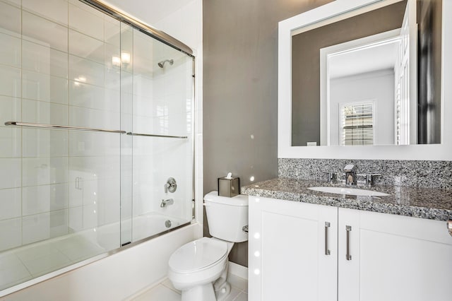 full bathroom featuring tile patterned floors, vanity, toilet, and bath / shower combo with glass door