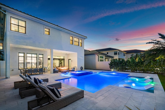 pool at dusk with a patio area and an in ground hot tub